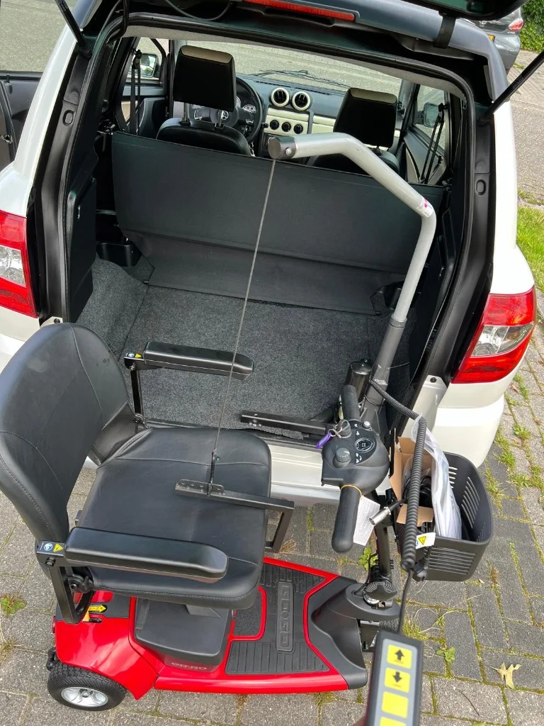 Scootmobiel wordt geladen met elektrische lift in achterbak